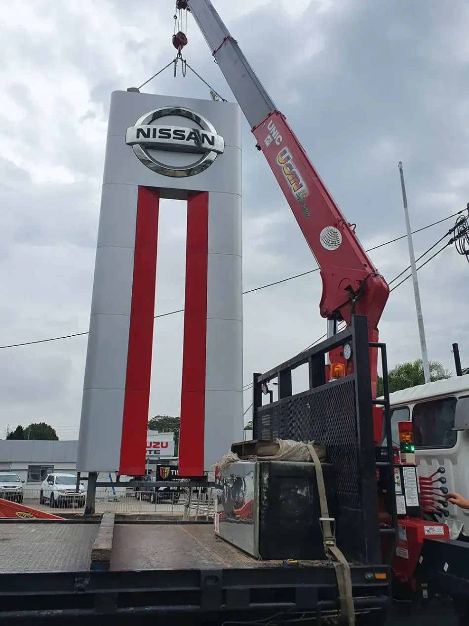 A nissan sign is being lifted by a crane