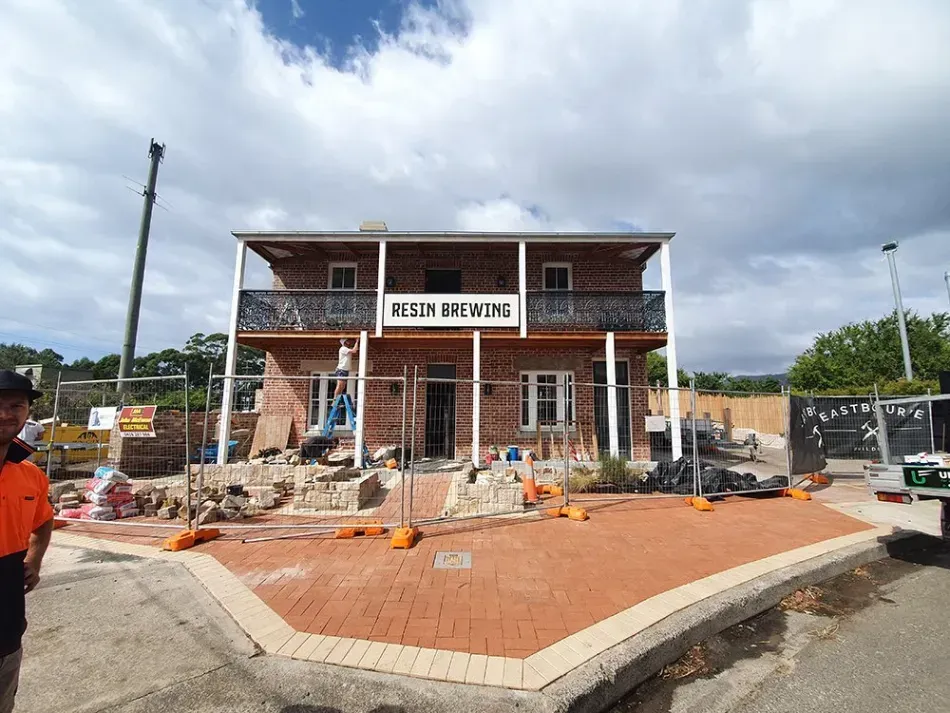 A man in an orange shirt is standing in front of a building under construction.
