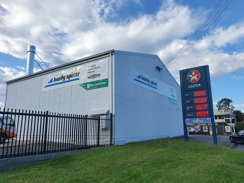 A large white building with a fence and a gas station in front of it.
