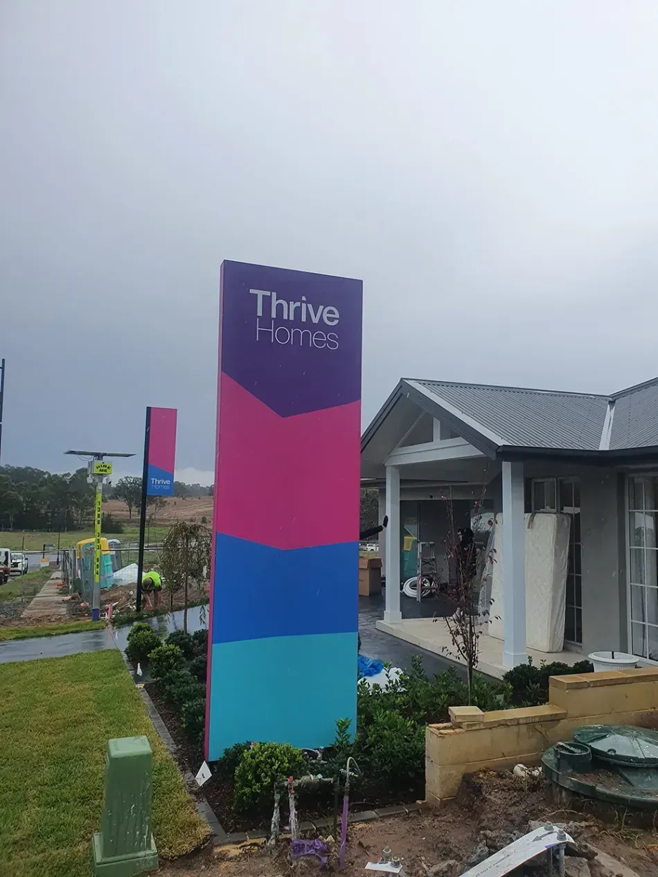 A large pink and blue sign is in front of a house.