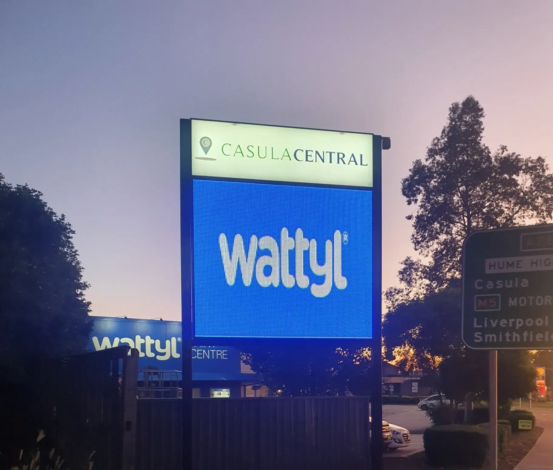 A sign for wattyl is lit up at night