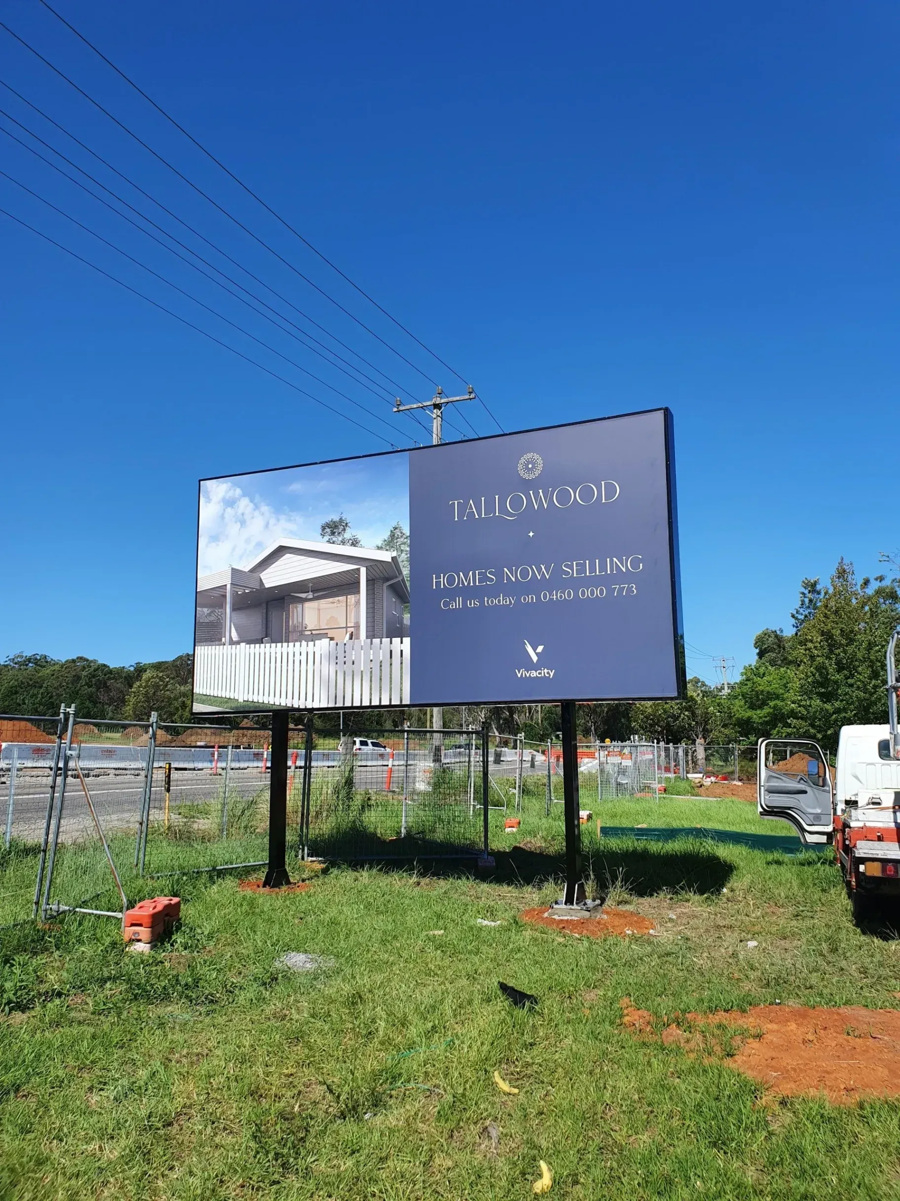 A large billboard is sitting in the middle of a grassy field.