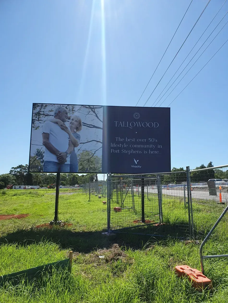A large billboard is sitting in the middle of a grassy field.