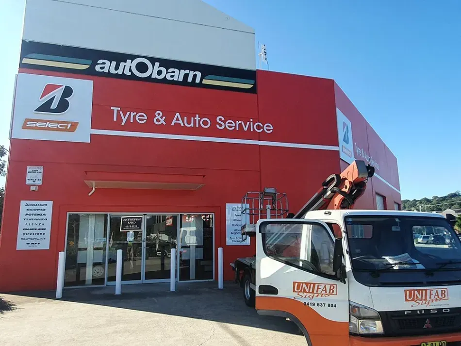 A truck is parked in front of a building that says autobarn tyre & auto service