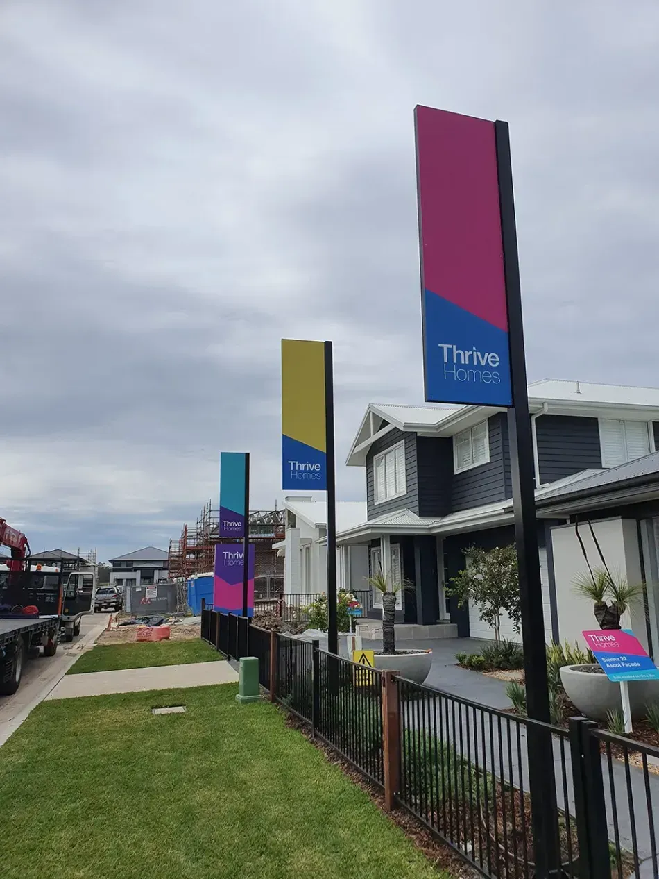 A row of colorful banners are hanging on a pole in front of a house.