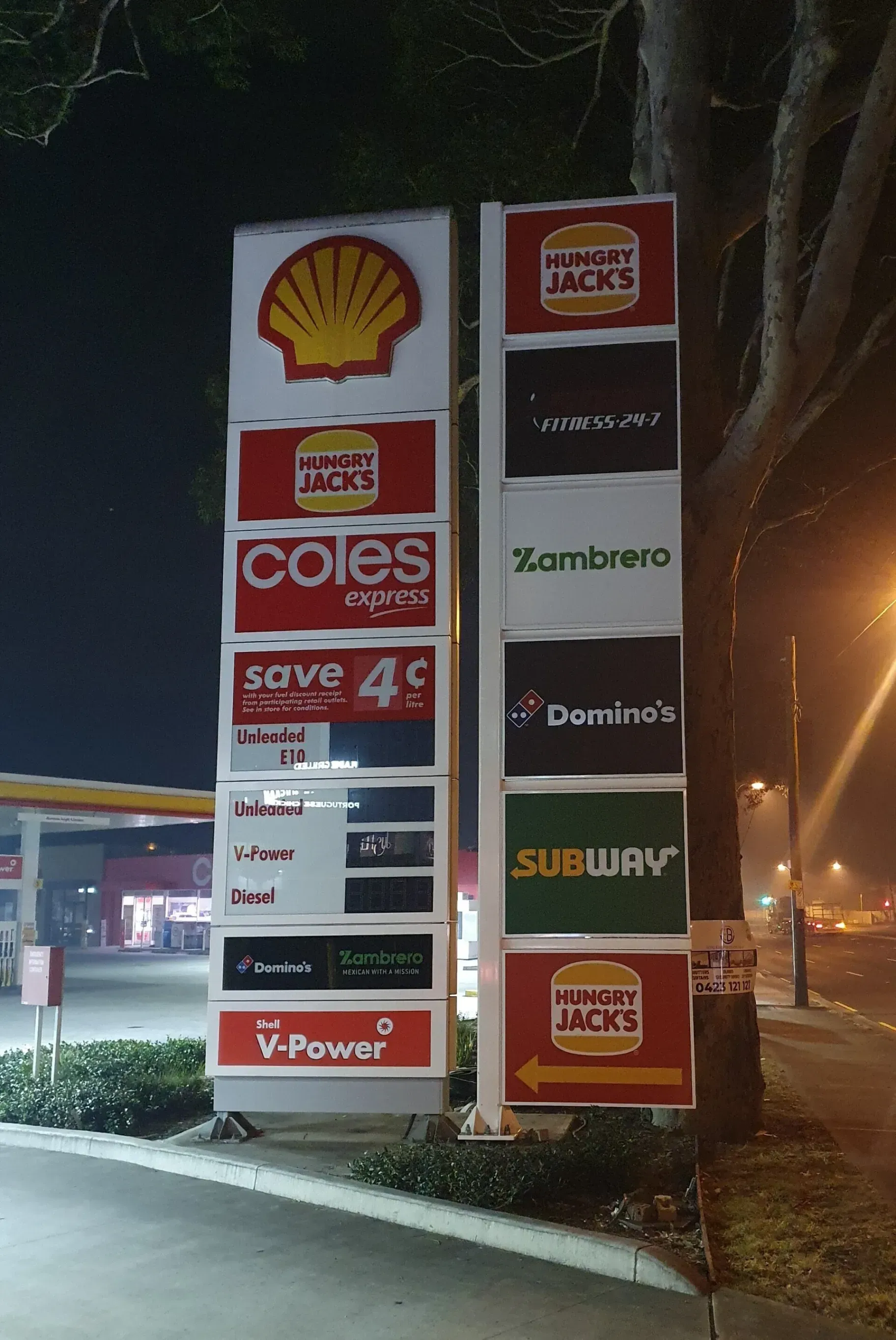 A shell gas station with coles subway and domino 's