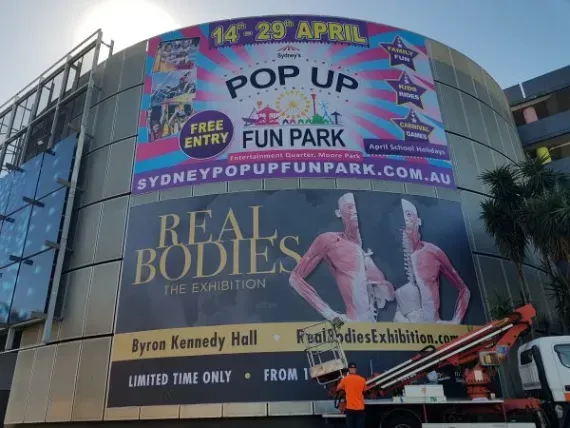 A large billboard on the side of a building that says pop up fun park