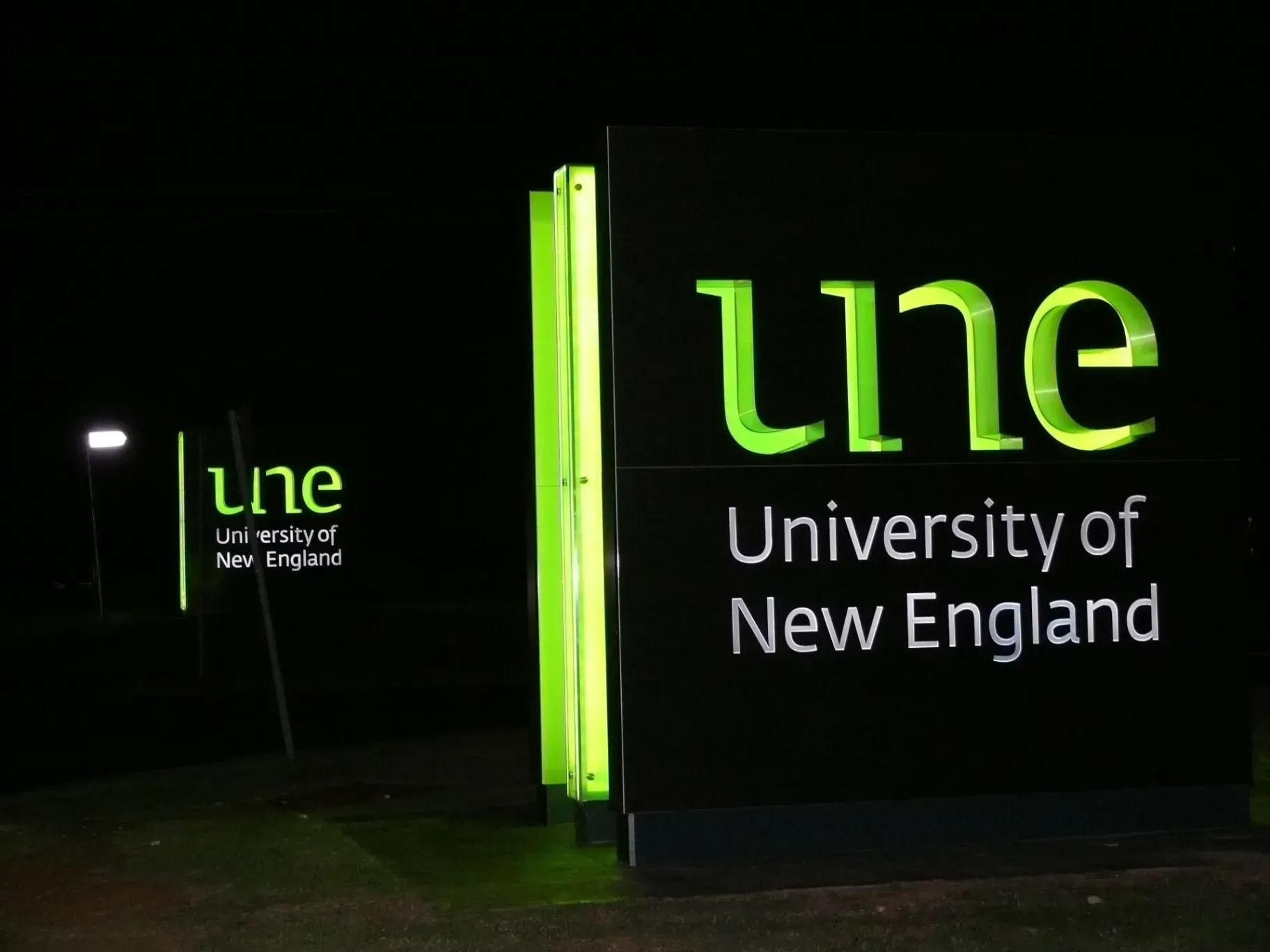 A sign for the university of new england is lit up at night