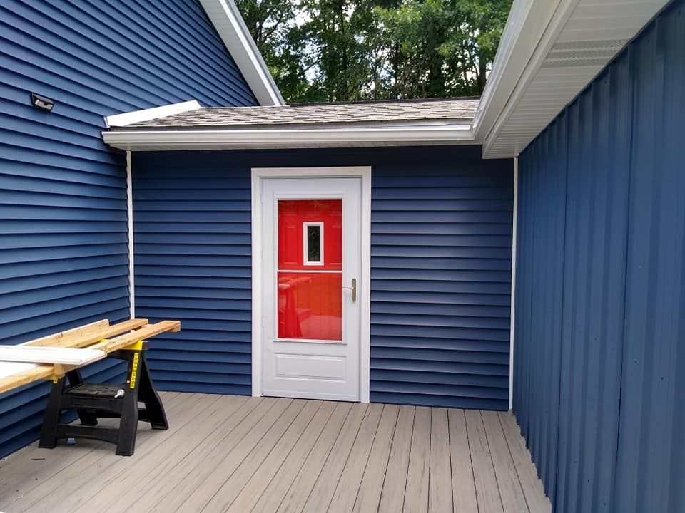 A blue house with a red door and a wooden deck