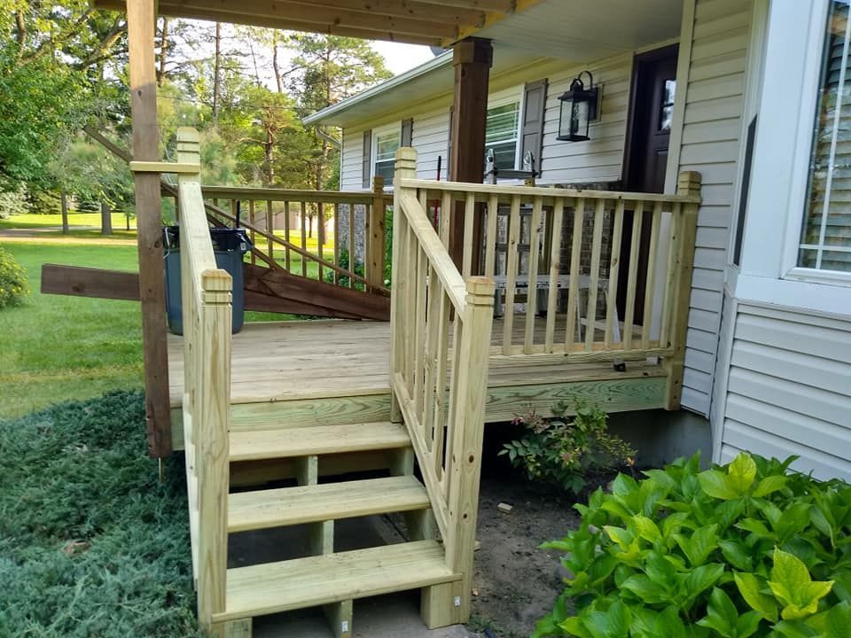 A wooden deck with stairs leading up to it is in front of a house.