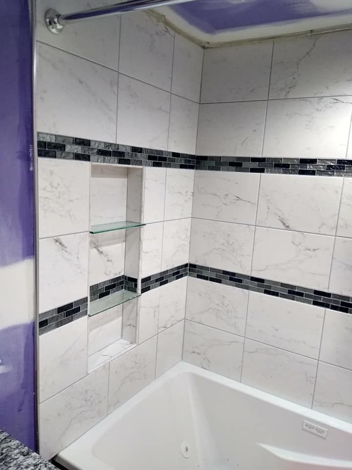 A bathroom with white tiles and a bathtub.