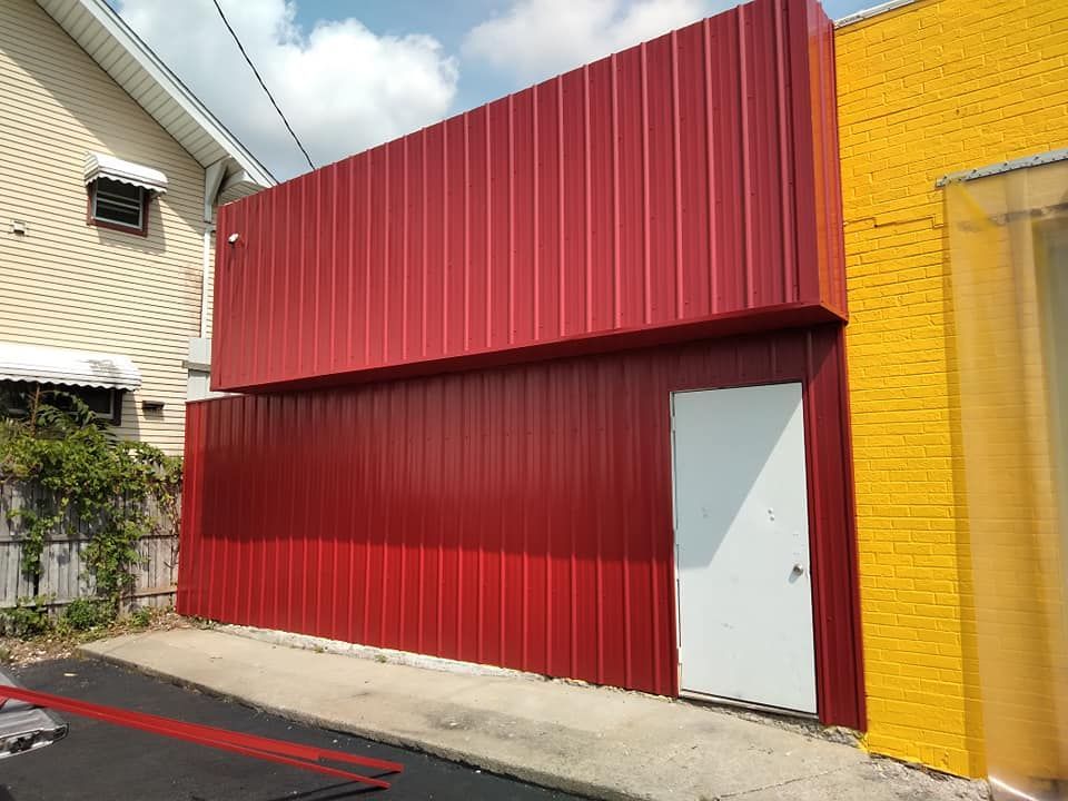 A red building with a white door is next to a yellow building.