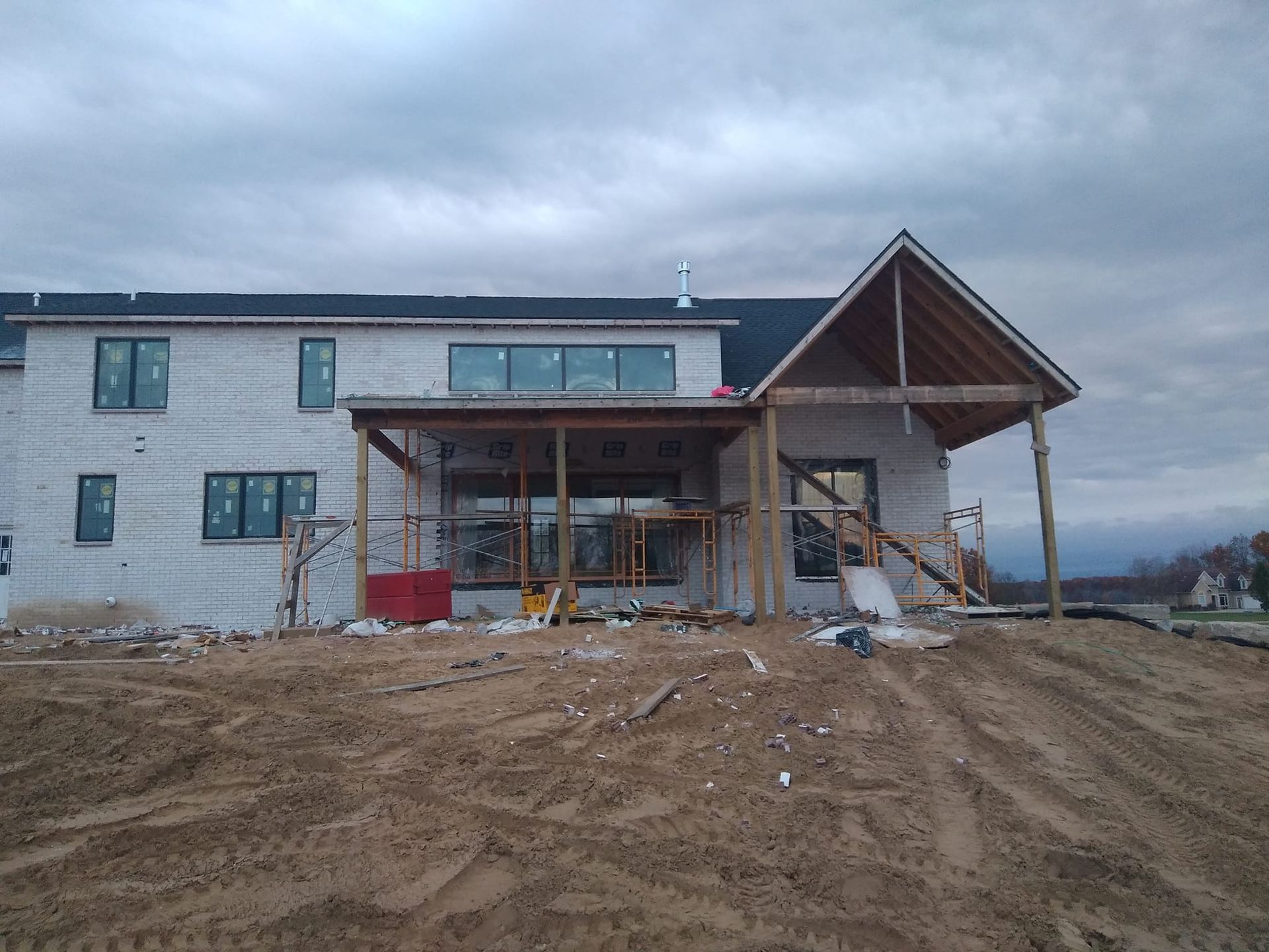 A large white house is being built in a dirt field.