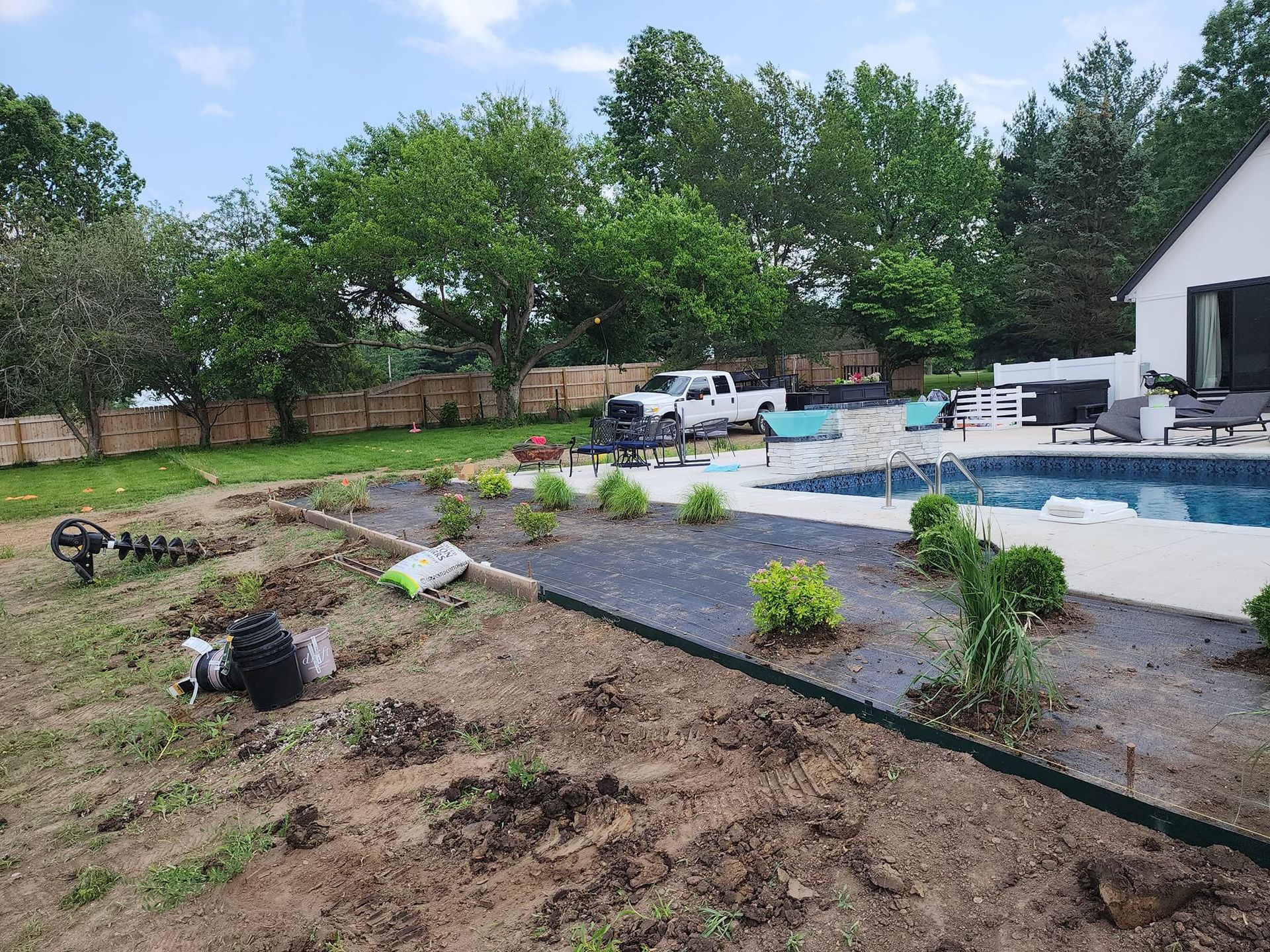 Backyard pool area with fresh landscaping, lounge chairs, and a white pool house under cloudy skies