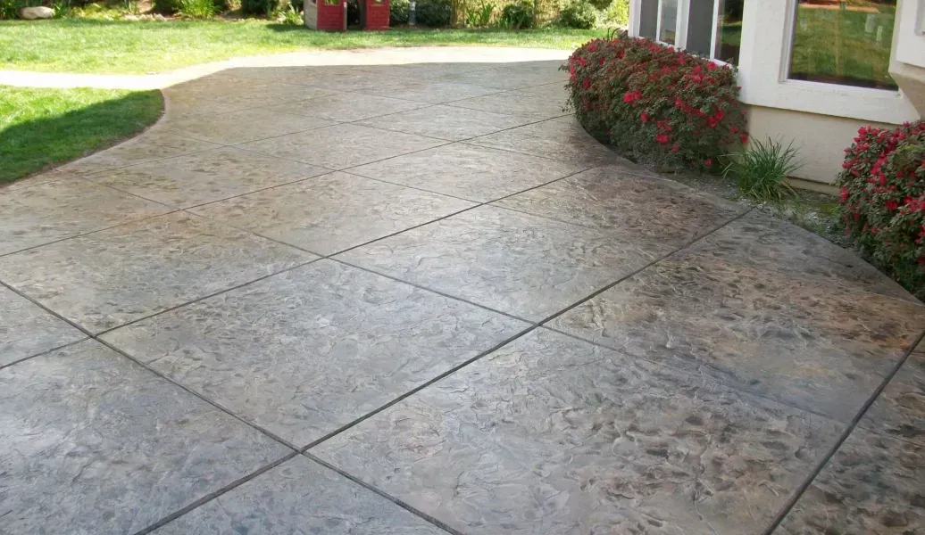 Gray concrete patio with fire pit, dining set, and lawn.