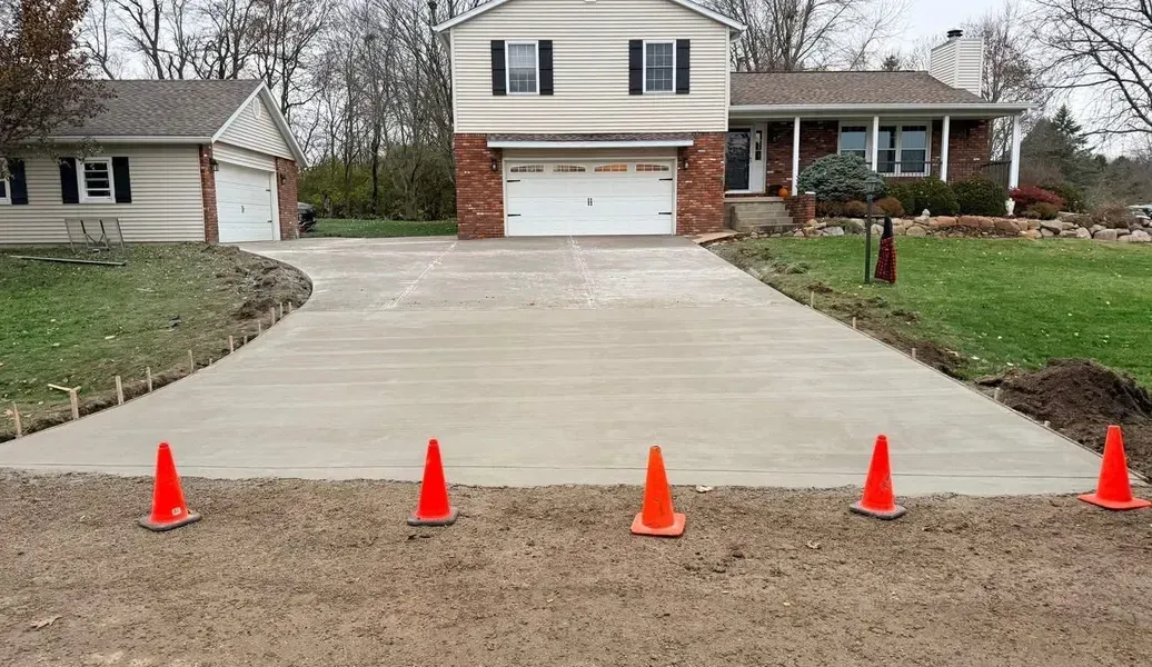Gray speckled epoxy-coated concrete porch floor, next to a darker concrete sidewalk, leading to a white door.