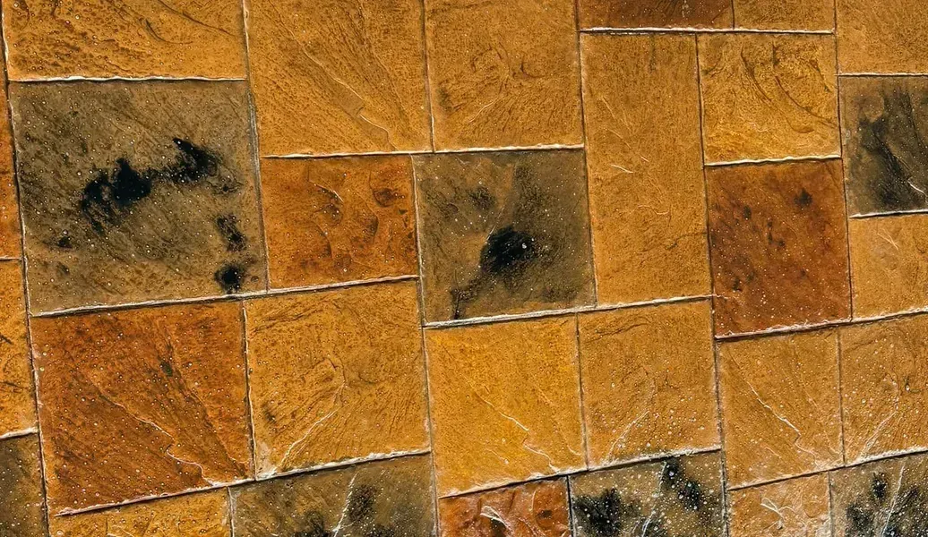 Square brown tiles laid out, with dark, wet patches.