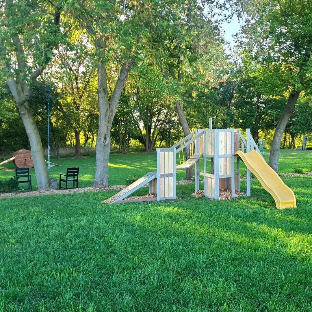 A wooden playground with a slide and a slide in a park.