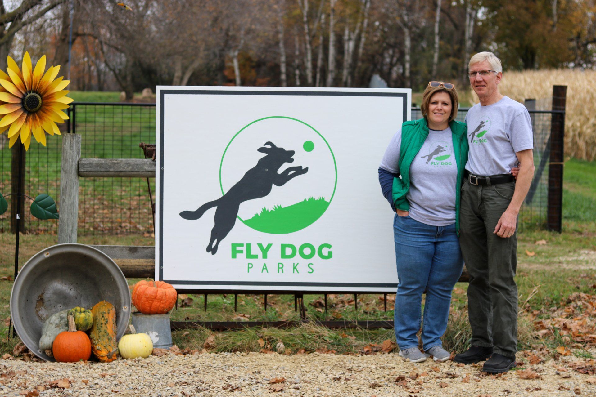A man and woman are standing in front of a sign for fly dog parks