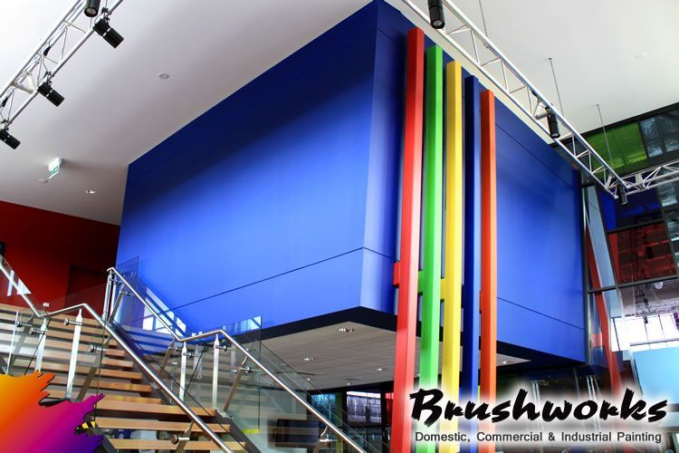 Interior view with a blue wall, colorful vertical pipes, and a staircase — Brushworks Painting In North Albury, NSW.