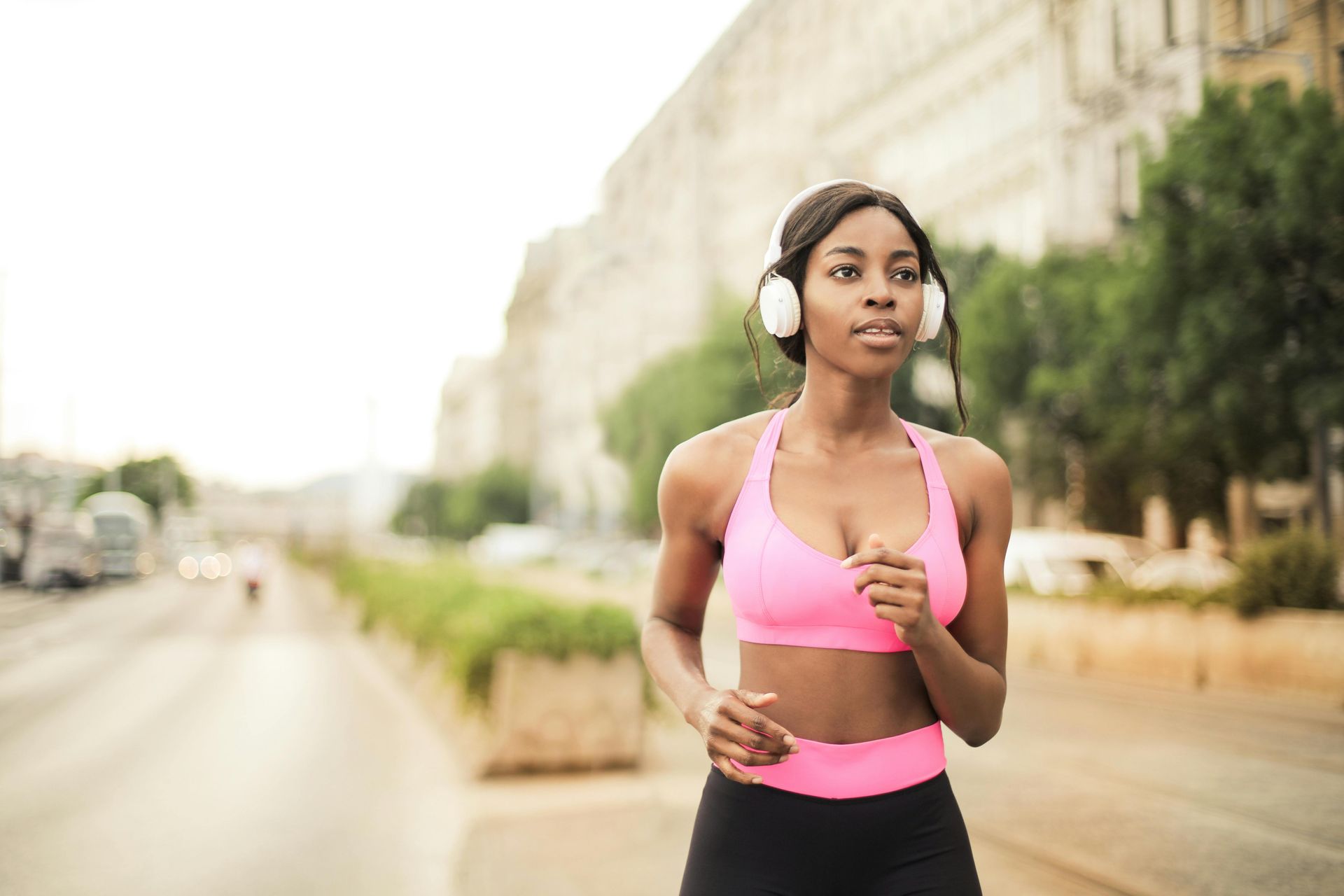 A woman wearing headphones is running down a city street.