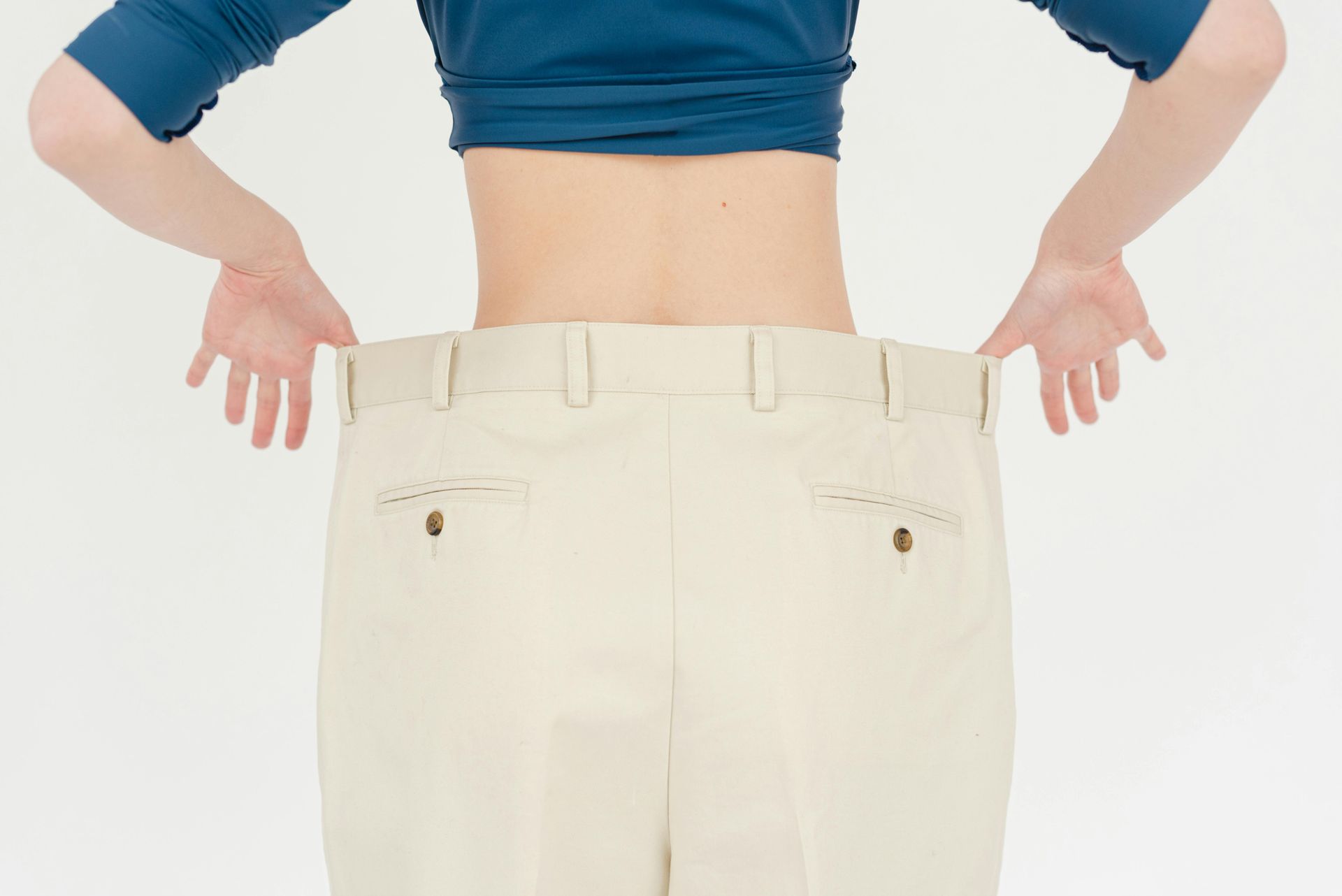 A woman is wearing a blue crop top and white pants.