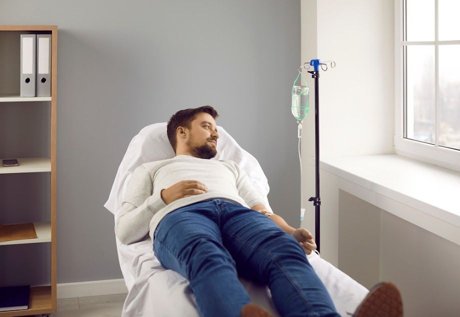 A man is laying in a hospital bed with an iv in his arm.