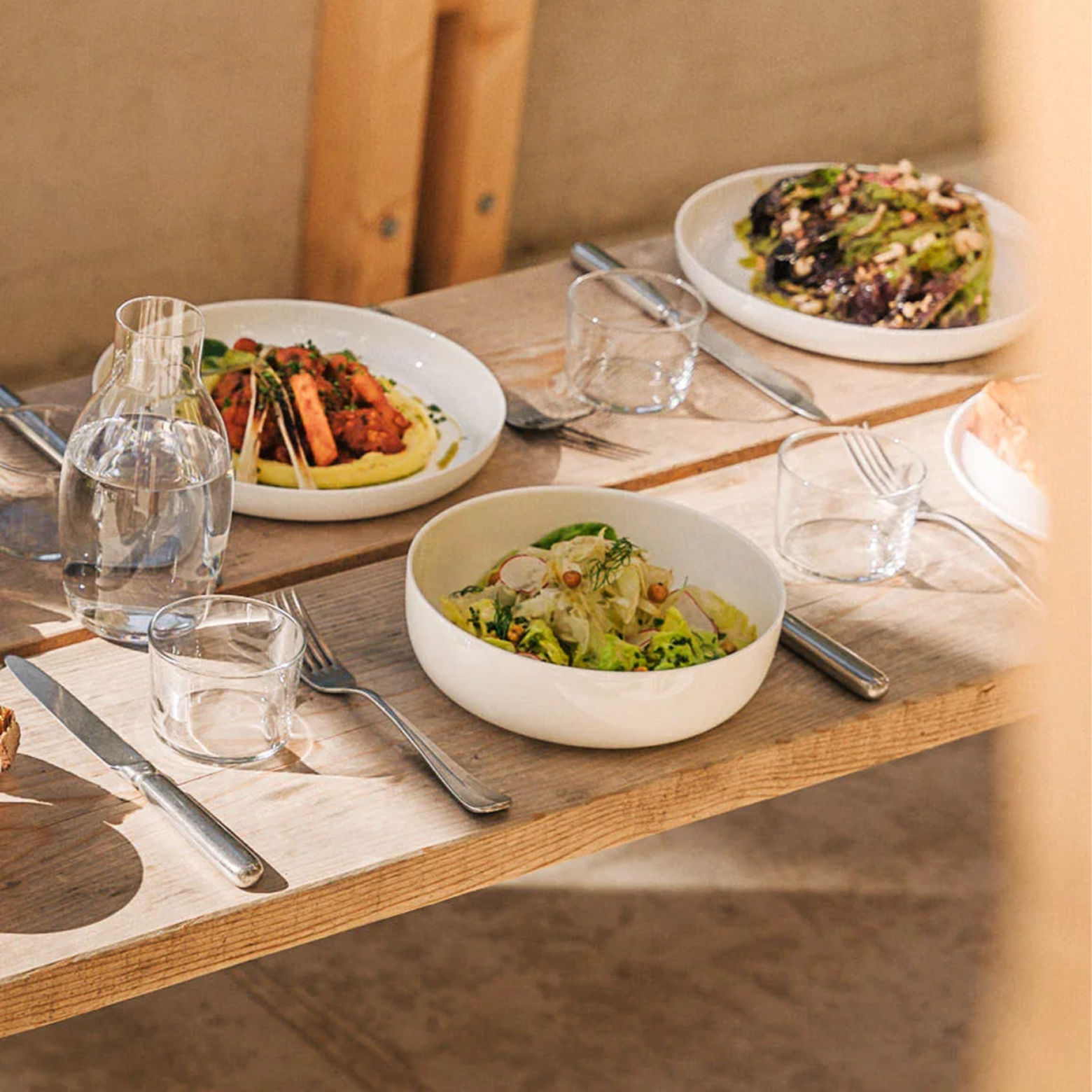 A basket of french fries sits on a table next to a plate of food.
