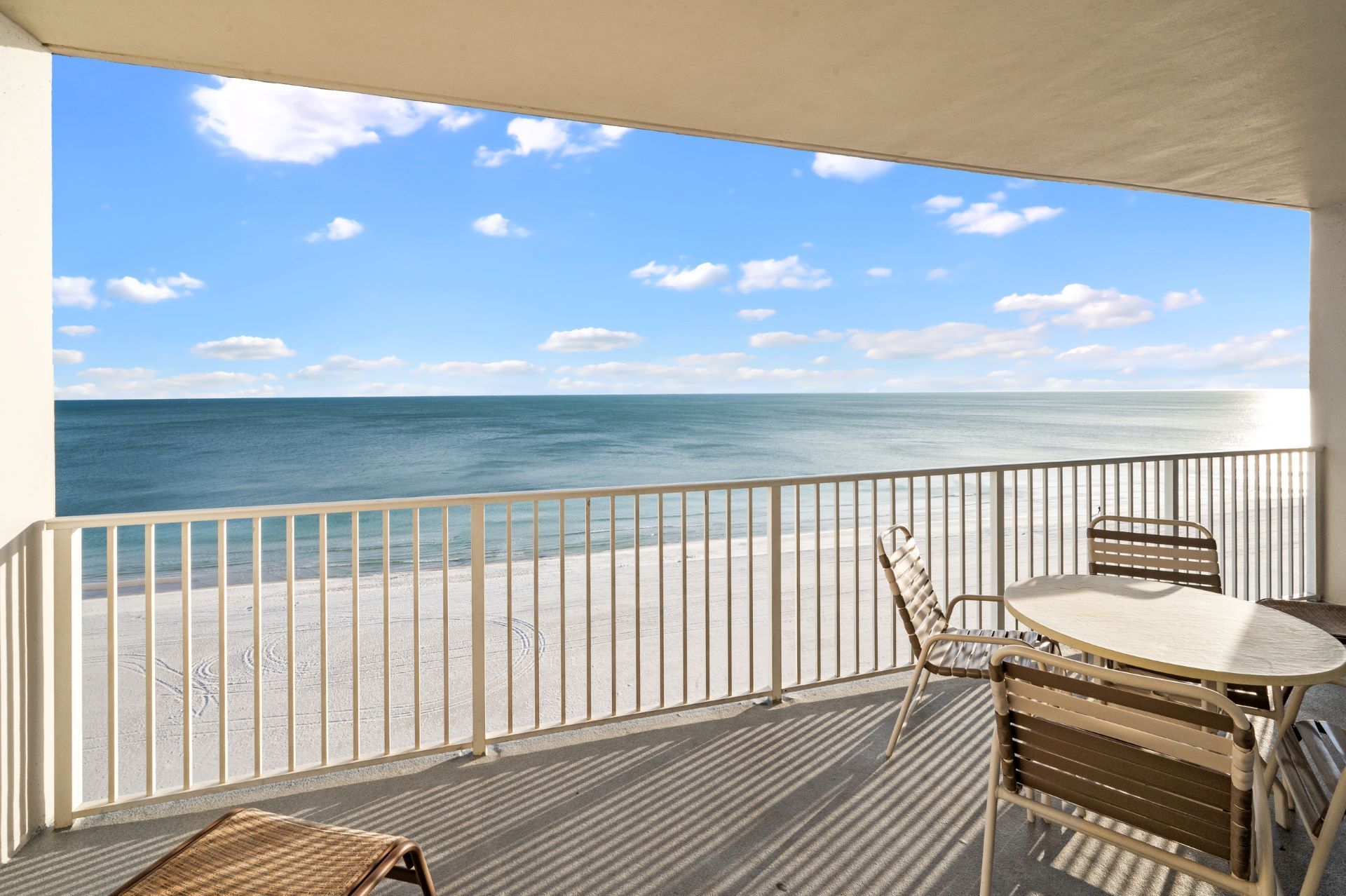 A balcony with a table and chairs overlooking the ocean.