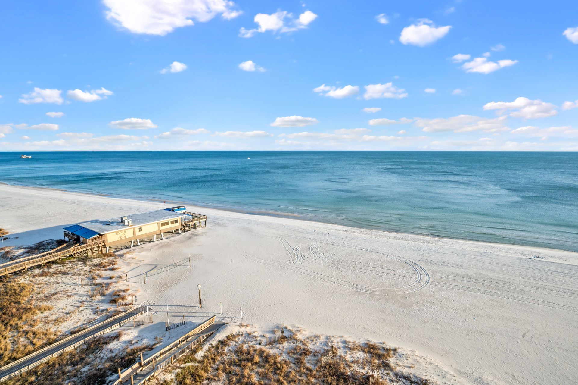 An aerial view of a beach with a house in the distance and the ocean in the background.
