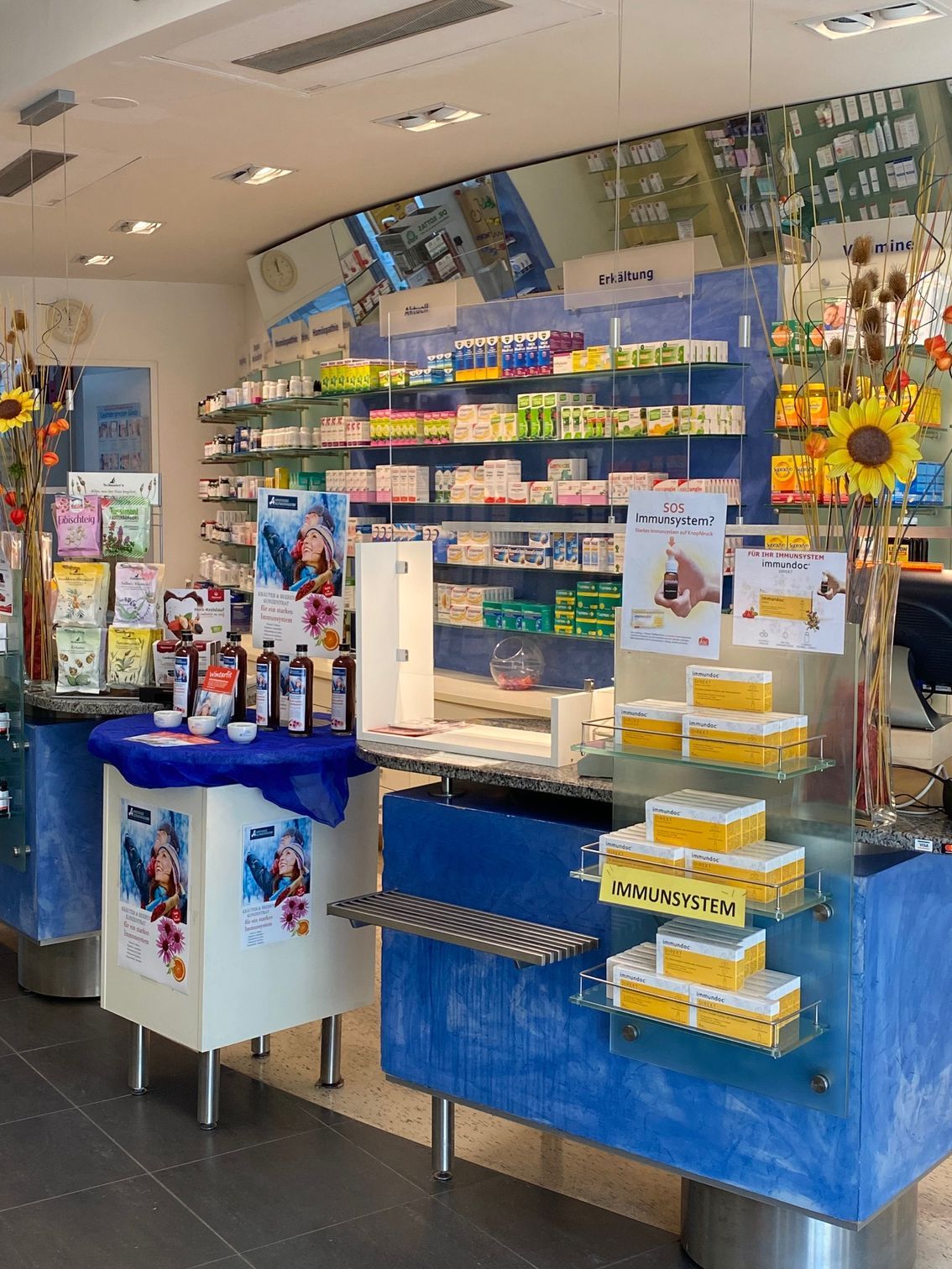 Ein leuchtend blauer Verkaufsstand mit Snacks, Getränken und Sonnenblumendekorationen in einem kleinen Laden