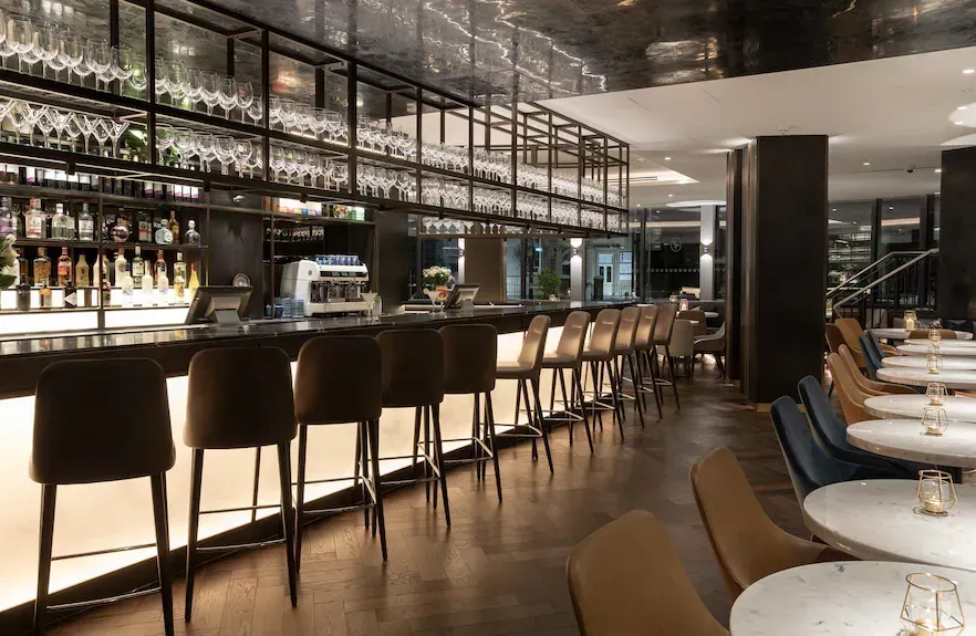 A restaurant with a long bar and tables and chairs