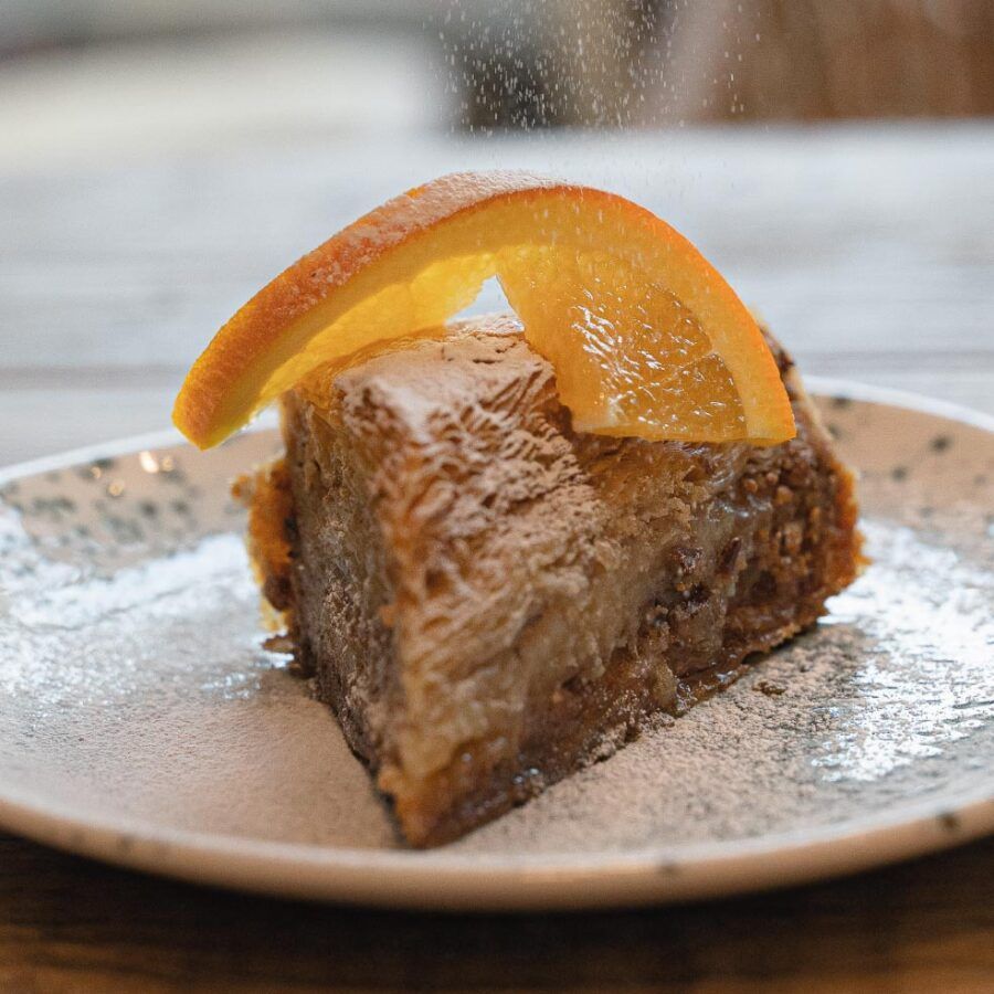 A slice of cake with an orange slice on top on a plate