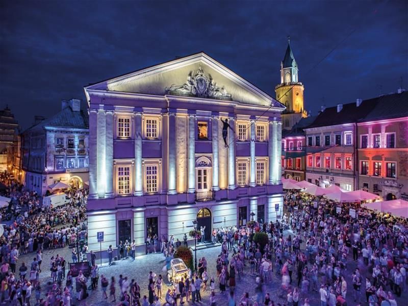 A crowd of people are gathered in front of a large building at night.