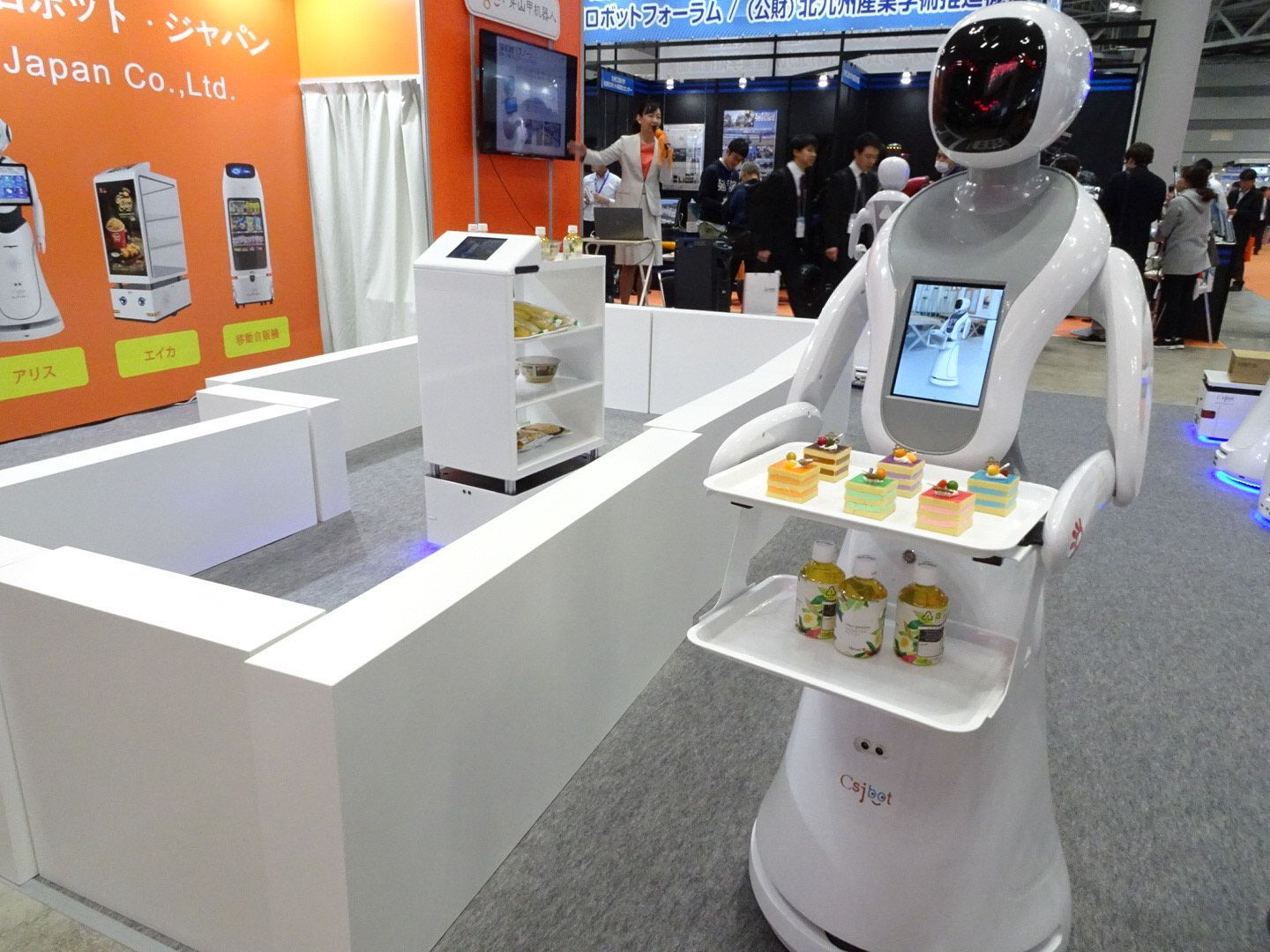 A robot is holding a tray of food in front of a sign that says japan co. ltd.