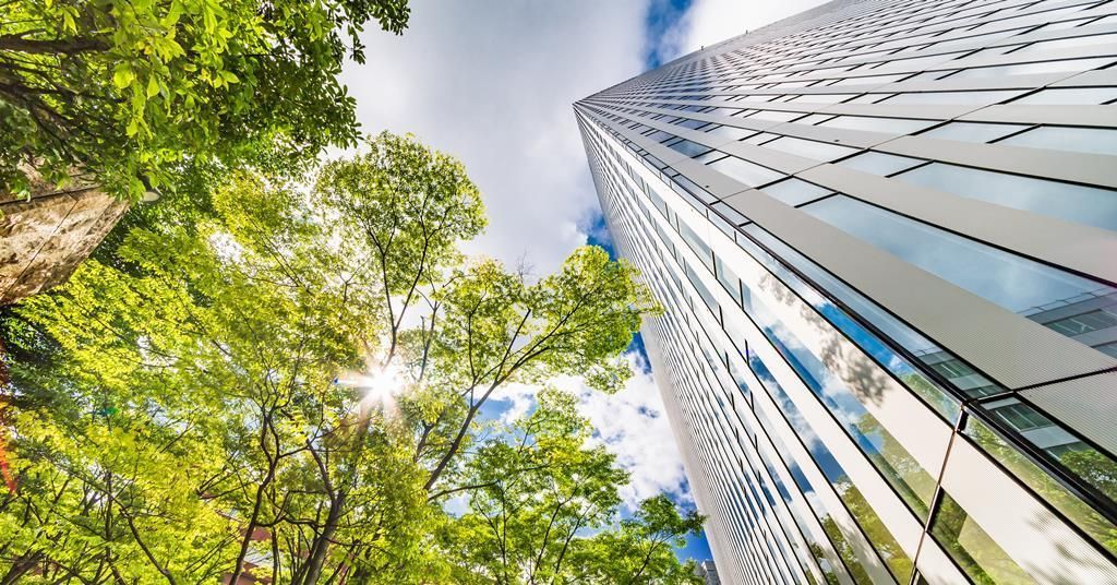 Looking up at a tall building with trees in front of it.