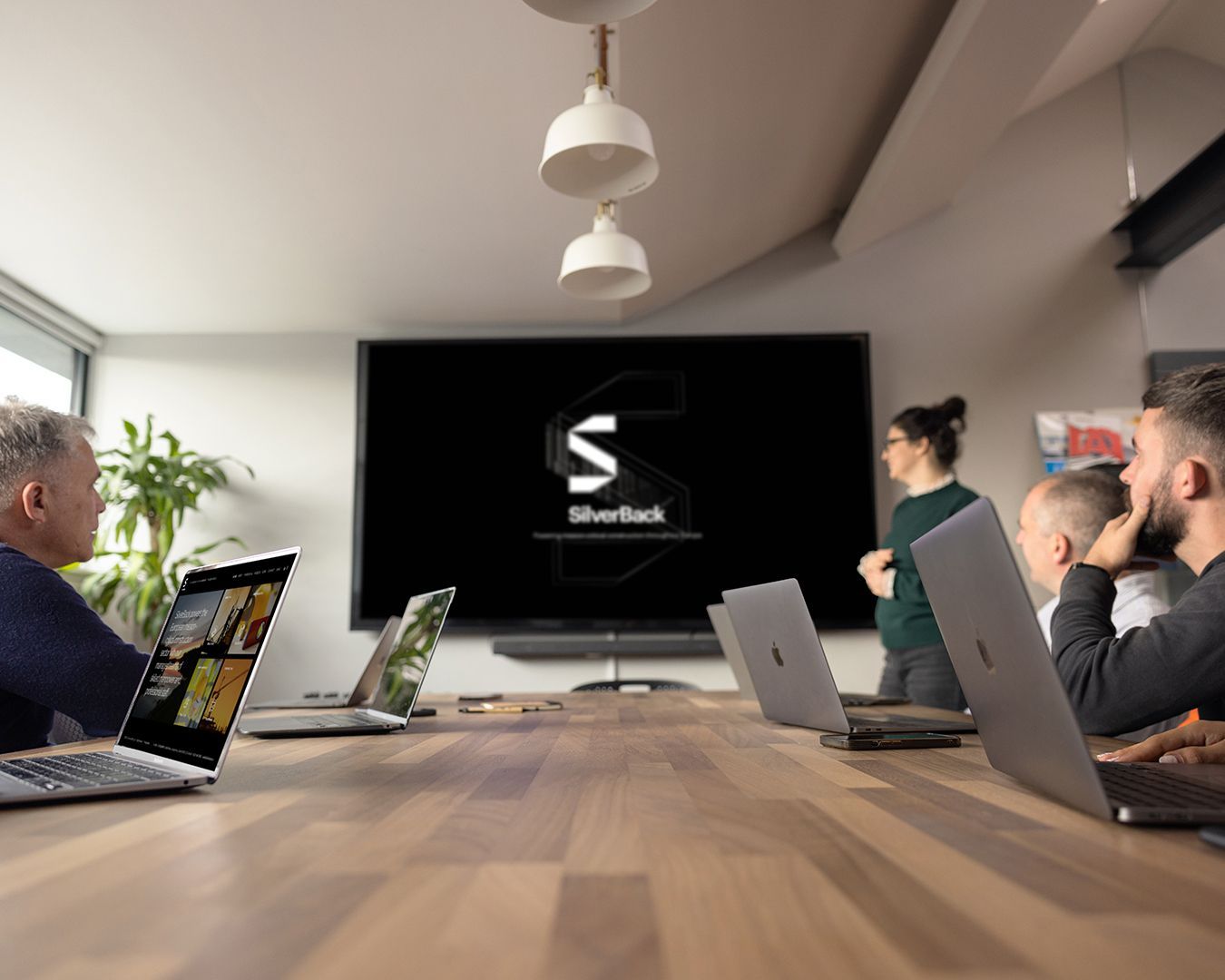 A group of people are sitting at a table with laptops in front of a large screen that says sherlock