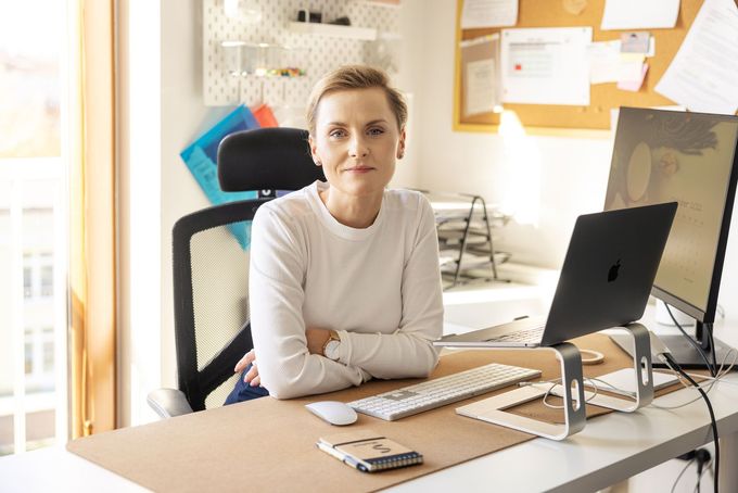 A woman is sitting at a desk with a laptop and a computer.