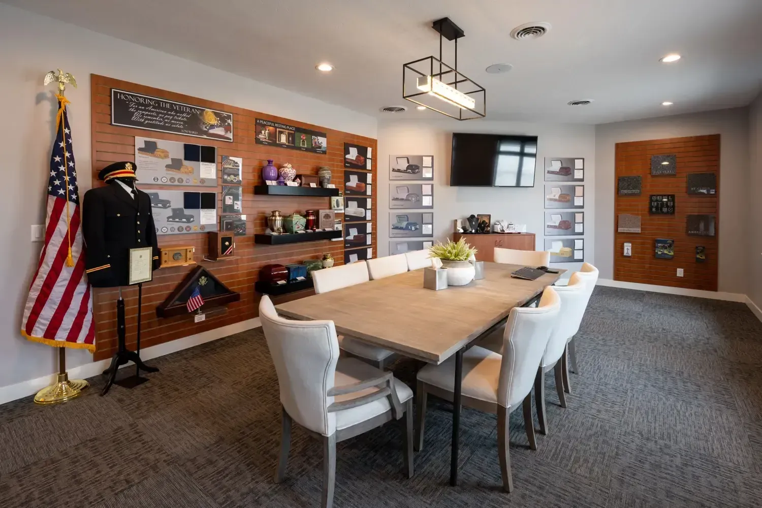 Modern conference room with wooden table, white chairs, wall shelves, and an American flag