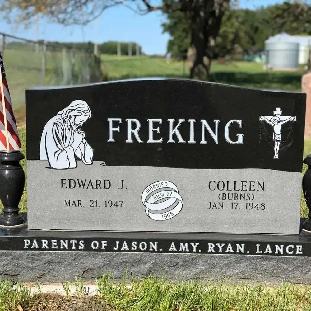 Black gravestone reading “FREKING” with engraved figures and names in a cemetery setting