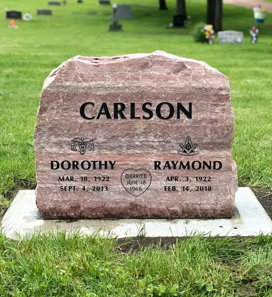 Pink granite CARLSON gravestone with Dorothy and Raymond names in a green cemetery lawn