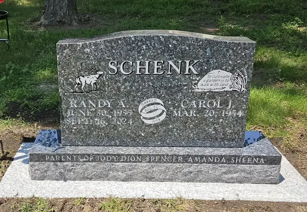 Stone memorial marker in a grassy cemetery, engraved with the name “SCHENK.”