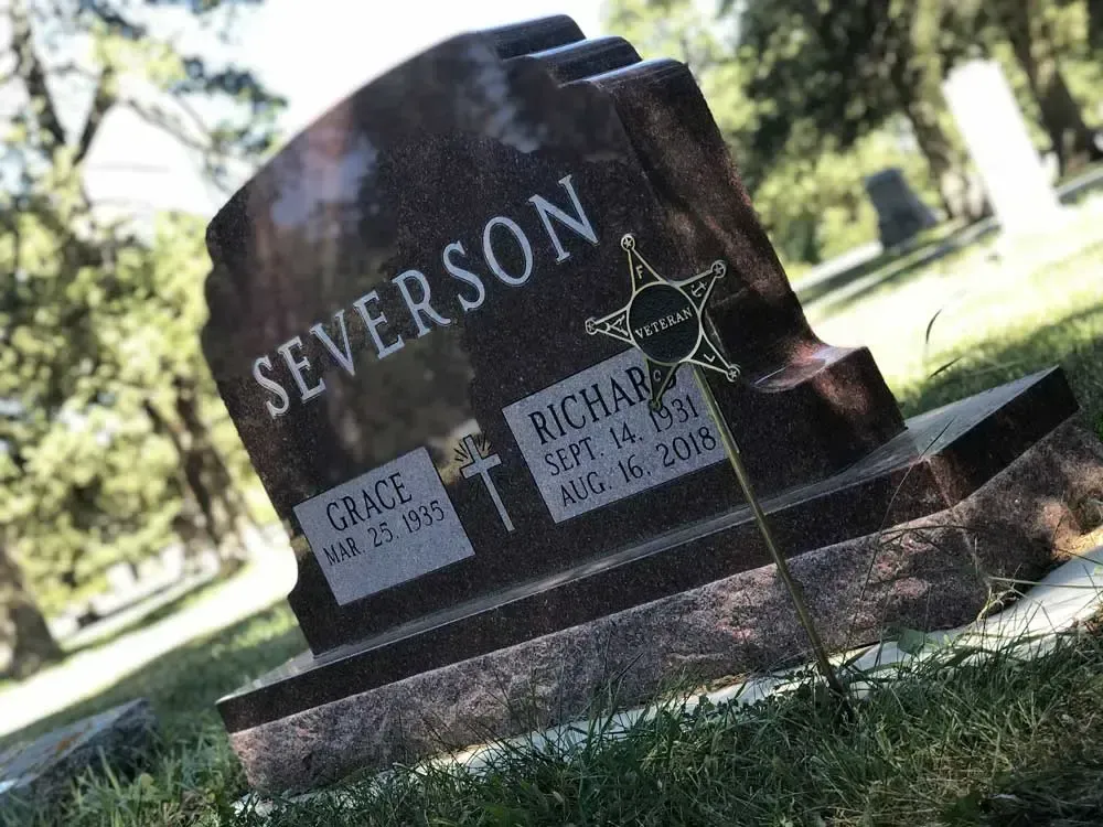 Tilted dark granite gravestone reading “SEVERSON” in a sunny cemetery