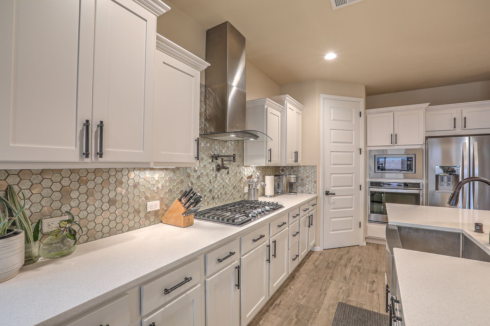 Bright modern kitchen with white cabinets, stainless steel appliances, and mosaic tile backsplash.