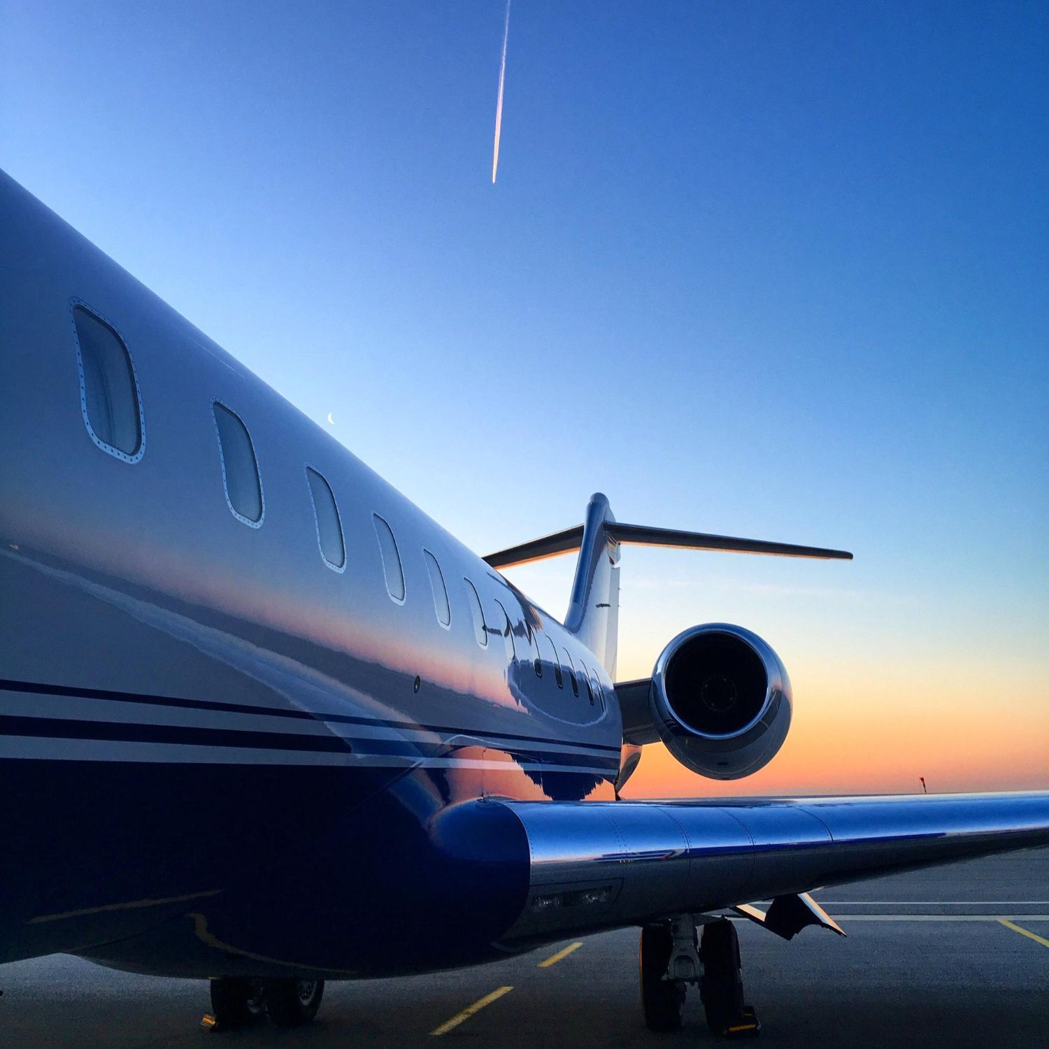An airplane is parked on a runway at sunset
