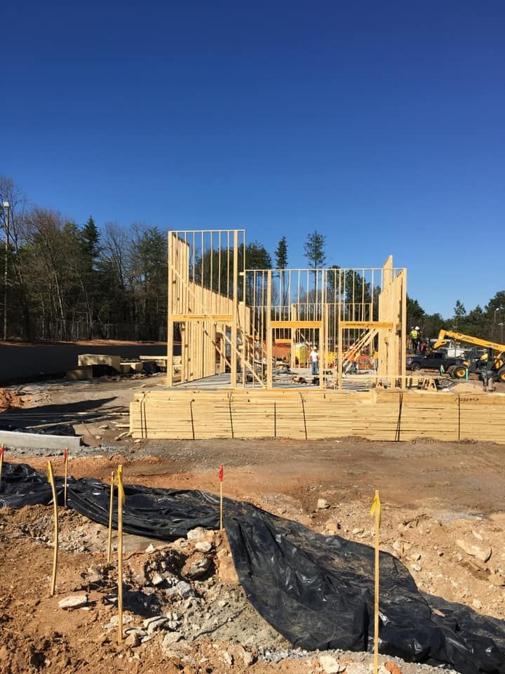 Construction site with wood framing of a building against a clear blue sky.