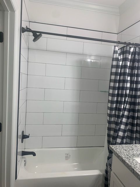 White tiled shower with black fixtures, a black and white checkered shower curtain, and white tub.