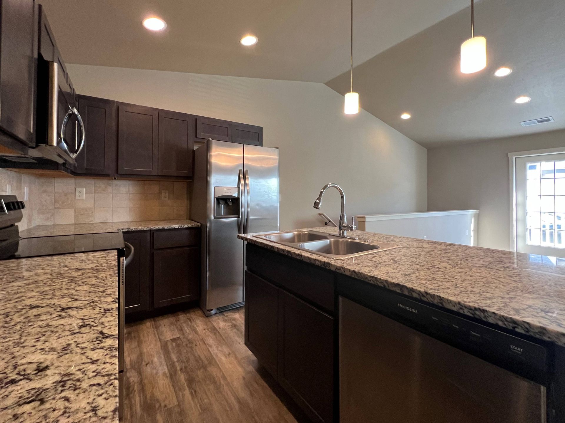 Modern kitchen with dark cabinetry, stainless steel appliances, and granite countertops.