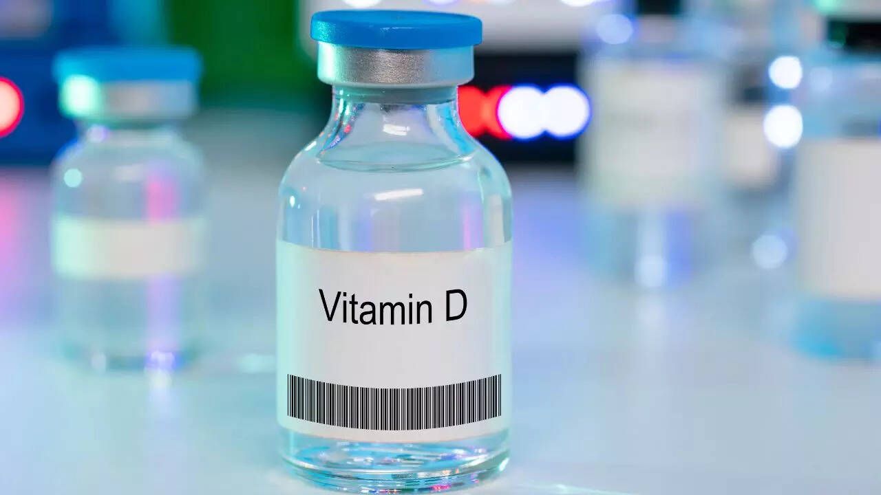Vitamin D vial with blue cap and barcode, standing on a blurred laboratory shelf.