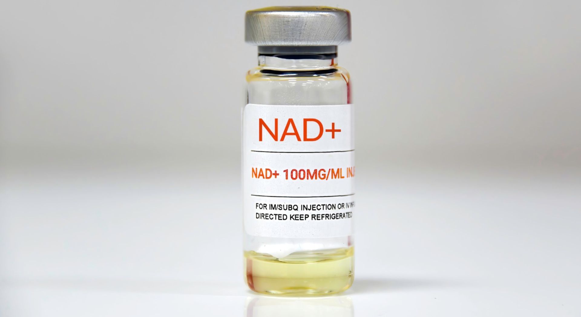NAD+ vial with silver cap and white label, filled with pale yellow liquid on a light background
